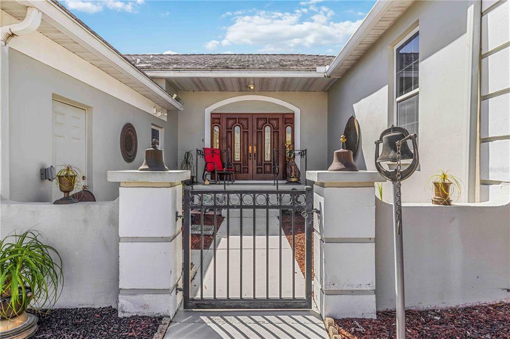 A gated courtyard leads to a double-door entrance of a stucco home — 4820 61ST AVENUE DRIVE W, BRADENTON, FL