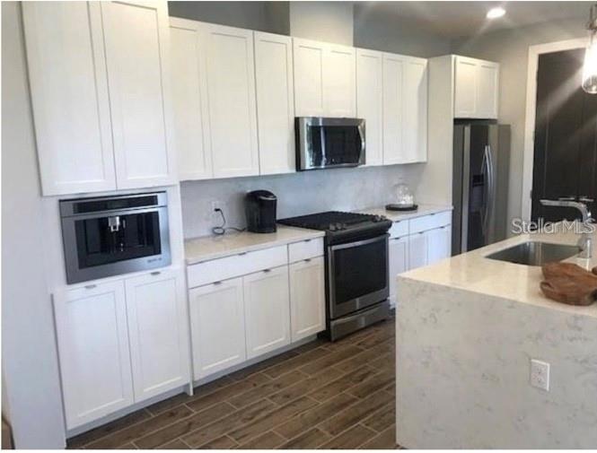 A modern kitchen features white cabinets, stainless steel appliances, and a quartz-topped island — 15349 SHONAN GOLD DRIVE, WINTER GARDEN, FL