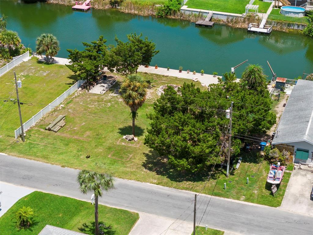 An aerial view shows a grassy waterfront lot with trees, a bulkhead, and a boat — 0 SEA GRAPE DR Lots 19 and 20, HERNANDO BEACH, FL