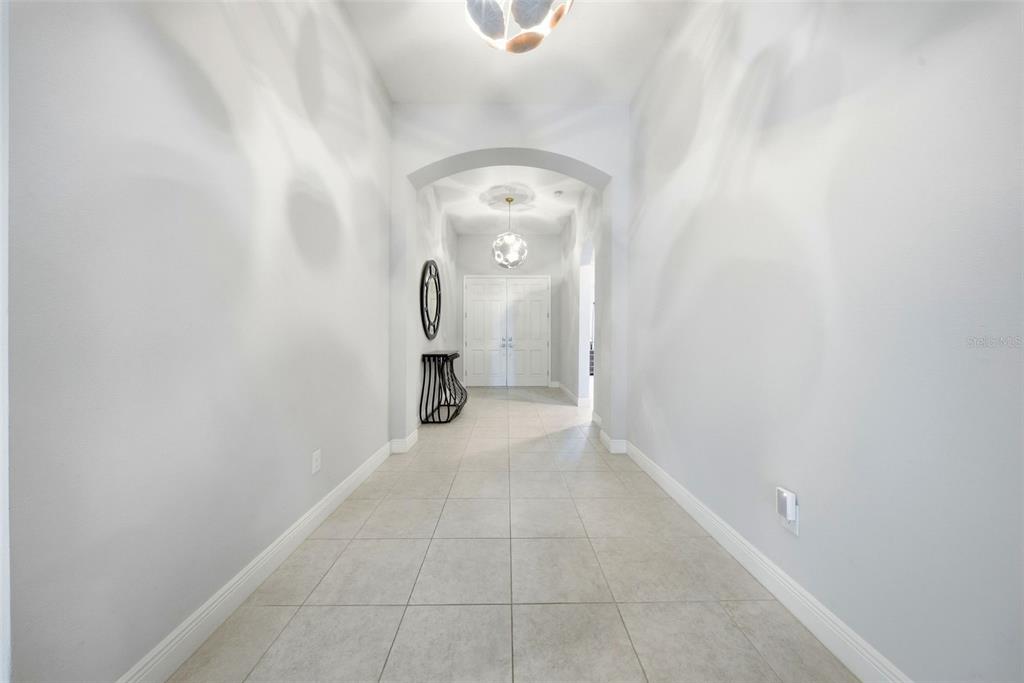 A bright, tiled entryway features an arched ceiling, two modern pendant lights, and white walls — 21813 BRISKE MORNING AVENUE, LAND O LAKES, FL