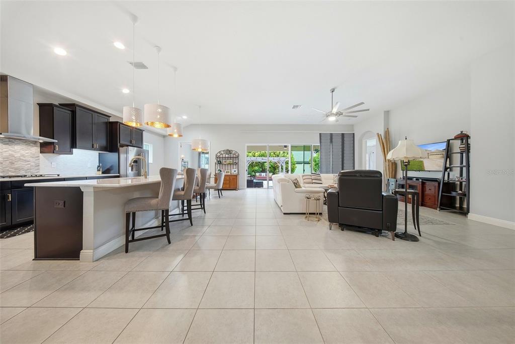 An open-concept kitchen and living area features tile flooring, dark cabinetry, and sliding glass doors — 21813 BRISKE MORNING AVENUE, LAND O LAKES, FL