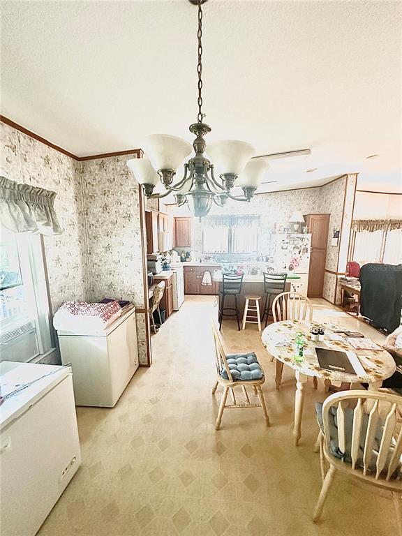 A kitchen and dining area features floral wallpaper, a chandelier, and a round wooden table — 11428 PHEASANT TRAIL, LEESBURG, FL