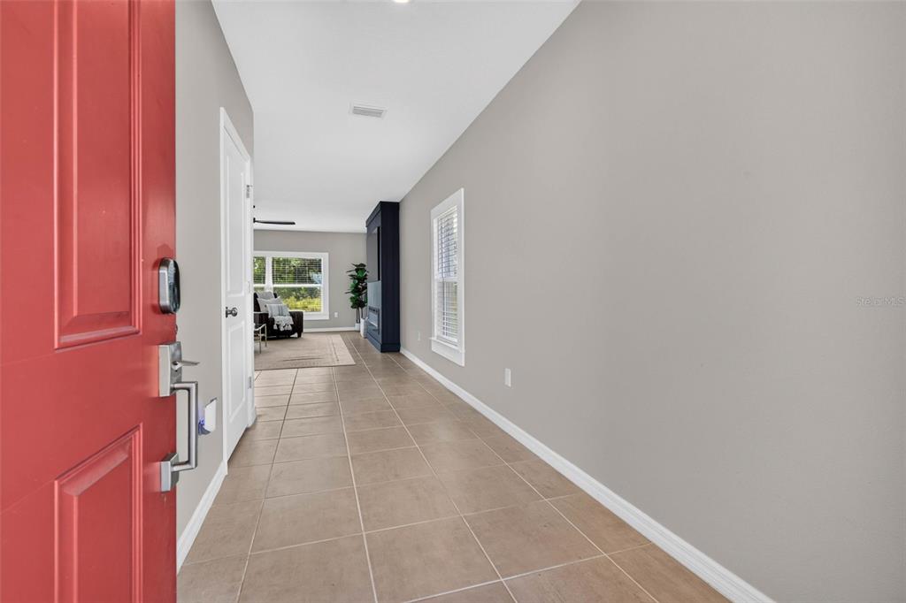 A view from a red front door into a hallway with tile flooring and gray walls — 5951 MAIDENSTONE WAY, PALMETTO, FL
