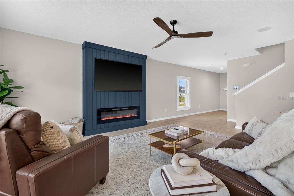 A living room features a blue shiplap accent wall with a mounted television and fireplace — 5951 MAIDENSTONE WAY, PALMETTO, FL