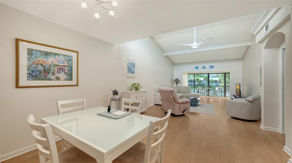 A dining area opens into a living room with vaulted ceilings and a balcony view — 1611 CLOWER CREEK DRIVE UNIT HA237, SARASOTA, FL
