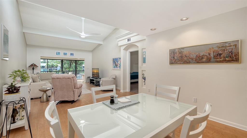 A bright dining area opens into a living room with vaulted ceilings and a balcony — 1611 CLOWER CREEK DRIVE UNIT HA237, SARASOTA, FL
