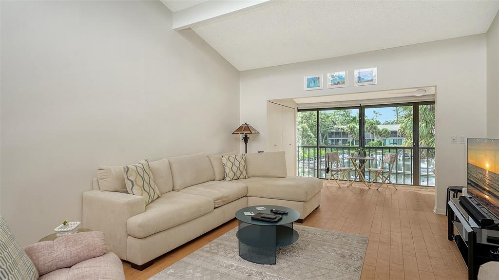 A living room with a beige sectional sofa, coffee table, and sliding doors to a balcony — 1611 CLOWER CREEK DRIVE UNIT HA237, SARASOTA, FL