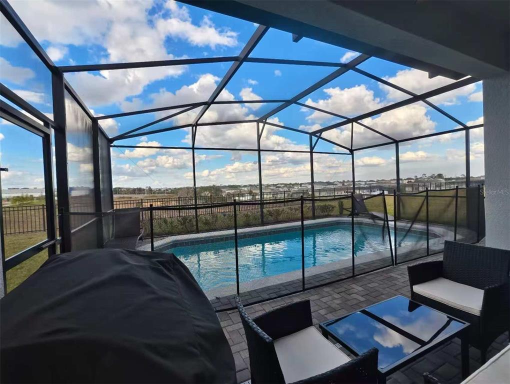 A screened-in patio features a swimming pool, outdoor furniture, and a view of the neighborhood — 2116 LELANI CIRCLE, DAVENPORT, FL