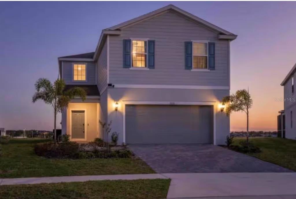 A two-story house with light gray siding, a two-car garage, and blue window shutters — 2116 LELANI CIRCLE, DAVENPORT, FL