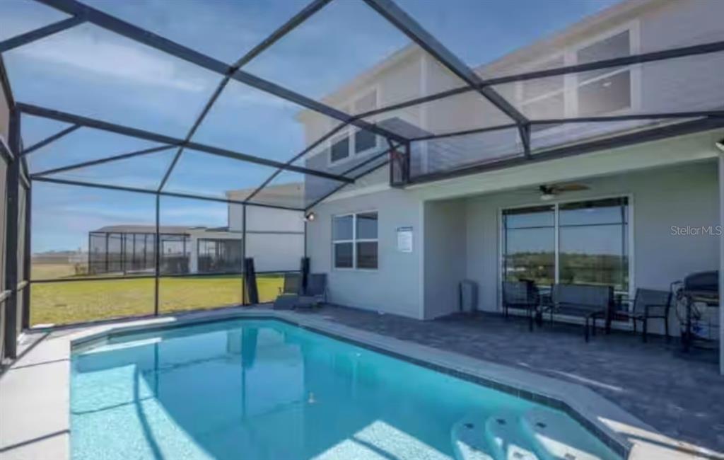 A screened-in patio features a rectangular swimming pool with steps and outdoor furniture — 2116 LELANI CIRCLE, DAVENPORT, FL