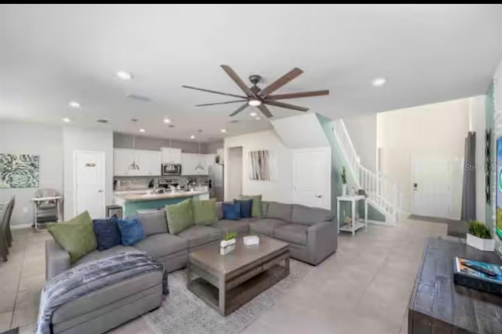 An open-concept living room features a large gray sectional, coffee table, and adjacent kitchen — 2116 LELANI CIRCLE, DAVENPORT, FL