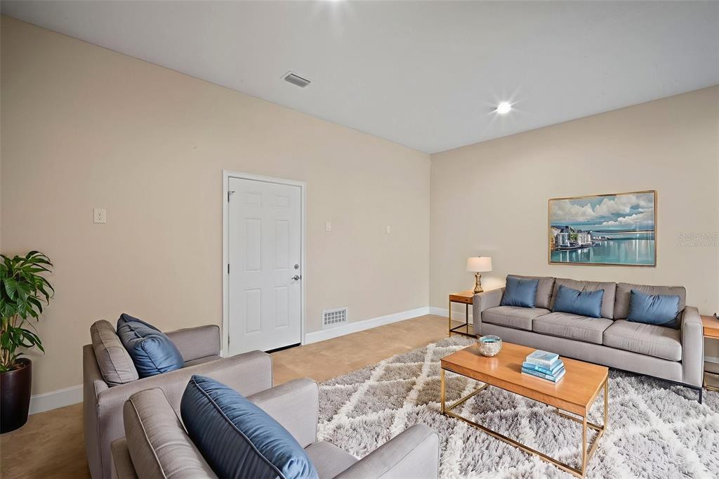 A living room features gray sofas, a patterned area rug, and a white door — 718 S 22ND STREET, TAMPA, FL