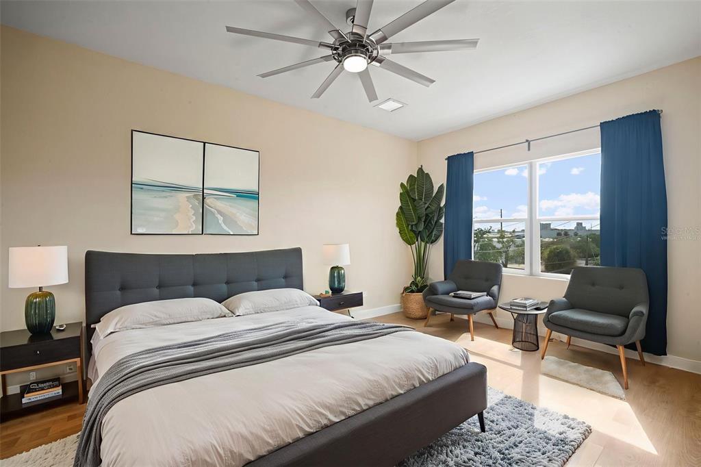 A bedroom features a gray upholstered bed, two armchairs, a ceiling fan, and large windows — 718 S 22ND STREET, TAMPA, FL