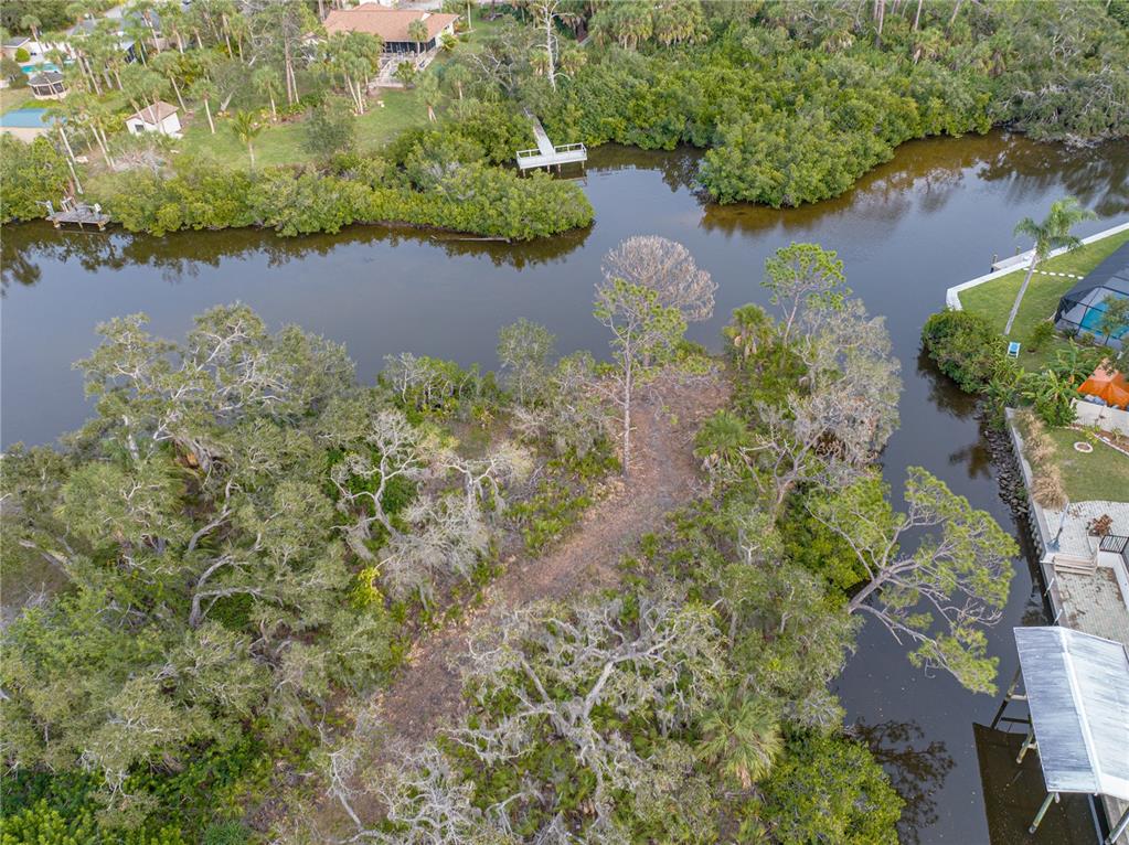 An aerial view of a wooded waterfront lot surrounded by a canal and residential properties — STRATFORD ROAD, ENGLEWOOD, FL