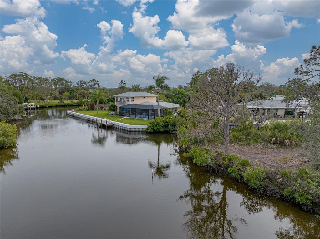 An aerial view shows a waterfront house with a screened pool deck along a canal — STRATFORD ROAD, ENGLEWOOD, FL