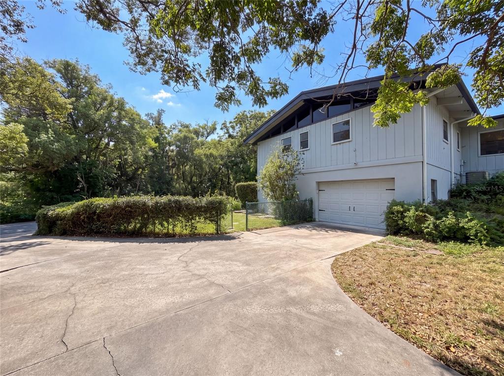 A two-story house with light-colored siding and a single-car garage sits beside a paved driveway — 925 PARK PLACE, DELAND, FL
