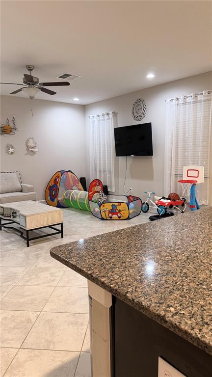 A living room with tile floors, a ceiling fan, a television, and children's play equipment — 9909 VICTORY GALLOP LOOP, RUSKIN, FL