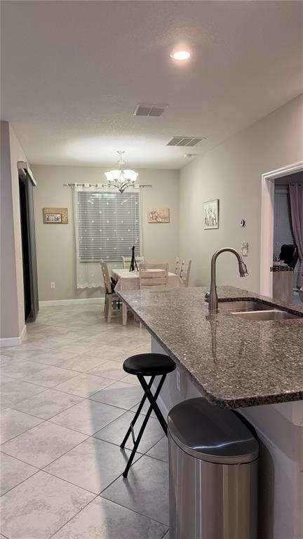 A kitchen island with a granite countertop overlooks a dining area with a chandelier — 9909 VICTORY GALLOP LOOP, RUSKIN, FL