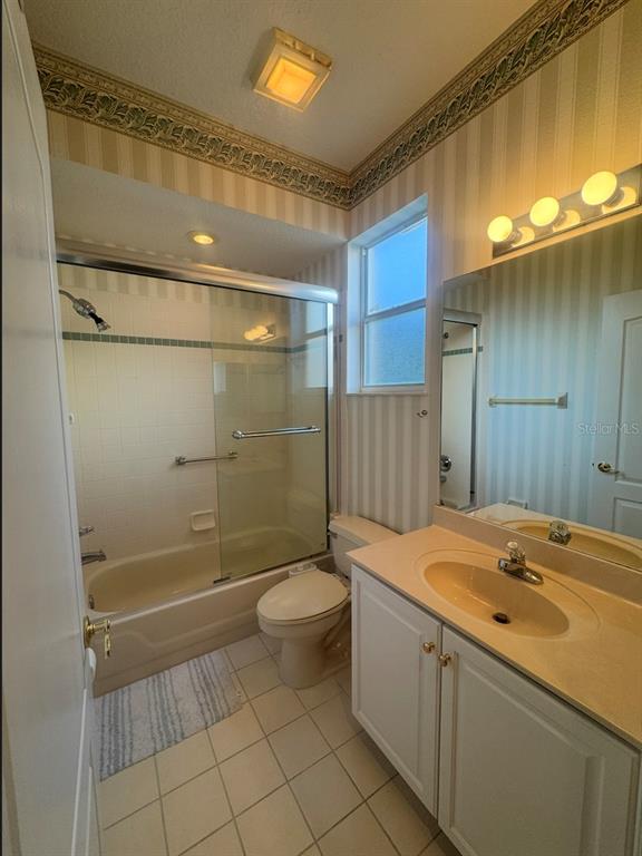A bathroom features a tub-shower combination, a vanity with a sink, and striped wallpaper — 10020 HONEY TREE COURT, ORLANDO, FL