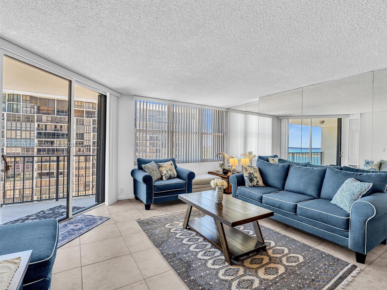 A living room features blue furniture, a coffee table, tile floors, and a mirrored wall — 1901 Brickell Ave # B1203, Miami FL 33129, MIAMI, FL