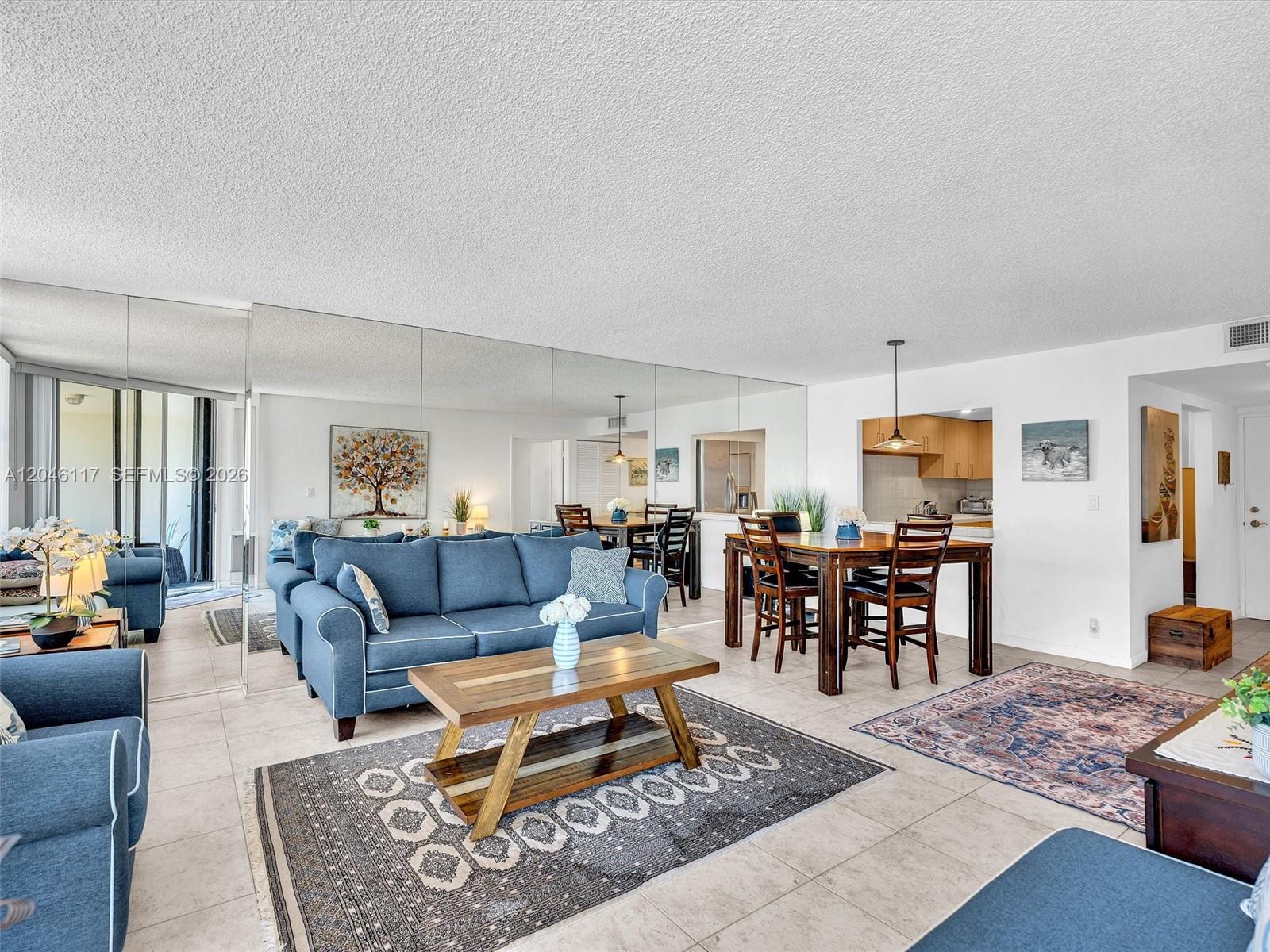 A living and dining area features a blue sofa, wooden furniture, and a mirrored wall — 1901 Brickell Ave # B1203, Miami FL 33129, MIAMI, FL
