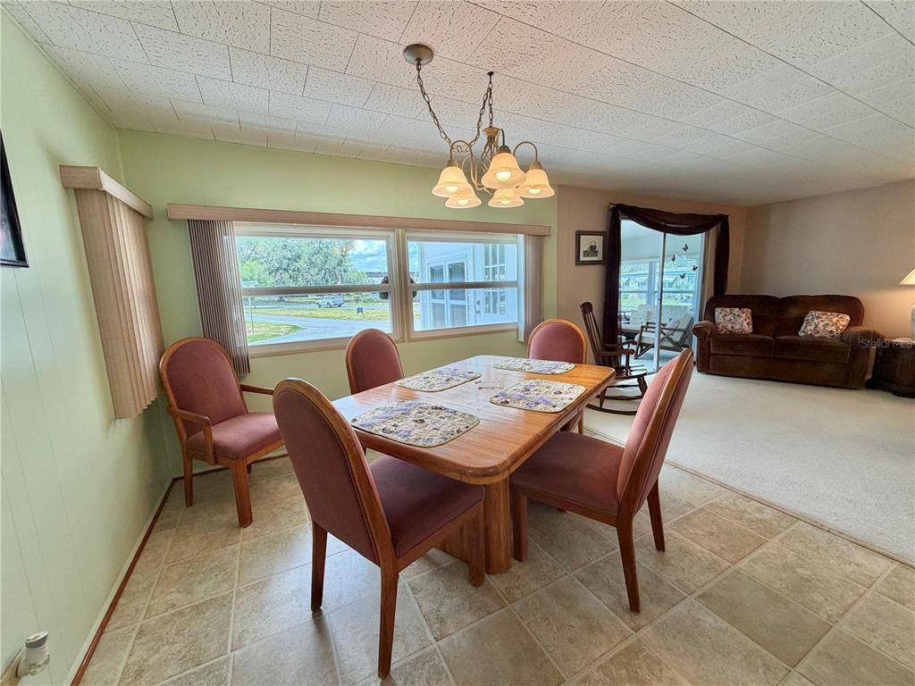 A dining area with a wooden table, four chairs, tile flooring, and a chandelier — 223 HAWTHORNE BOULEVARD, LEESBURG, FL