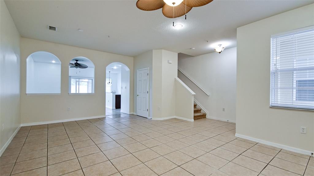 A living room features beige tile flooring, arched wall openings, and a staircase — 3497 PARKRIDGE CIRCLE UNIT 16-102, SARASOTA, FL