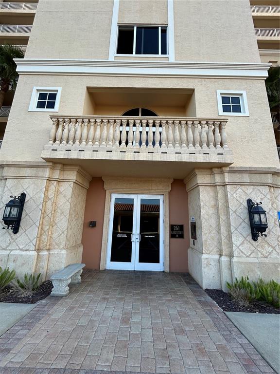 A multi-story residential building stands behind a pond with a fountain and landscaped grounds — 261 MINORCA BEACH WAY UNIT 203, NEW SMYRNA BEACH, FL