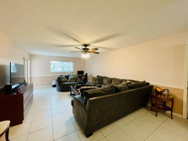 A living room features a large sectional sofa, tile flooring, and a ceiling fan — 22755 SW 66th Avenue # 103, Boca Raton FL 33428, BOCA RATON, FL