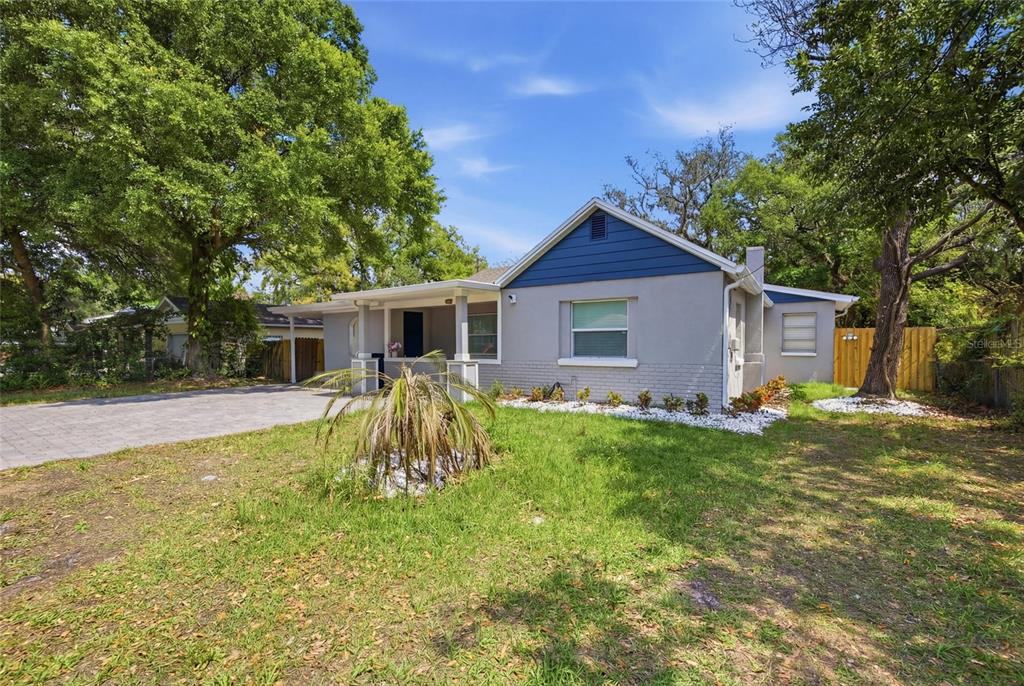 A single-story house with a gray exterior, blue gable siding, and a paved driveway — 5809 N 17TH STREET, TAMPA, FL