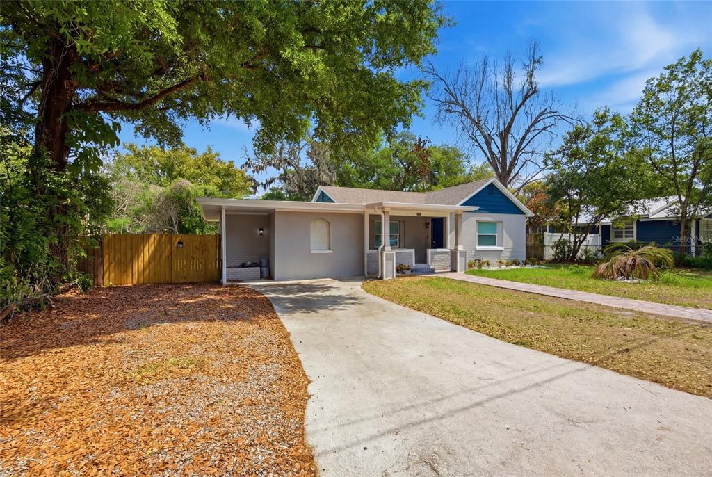 A single-story house with a concrete driveway, a wooden fence, and a front porch — 5809 N 17TH STREET, TAMPA, FL