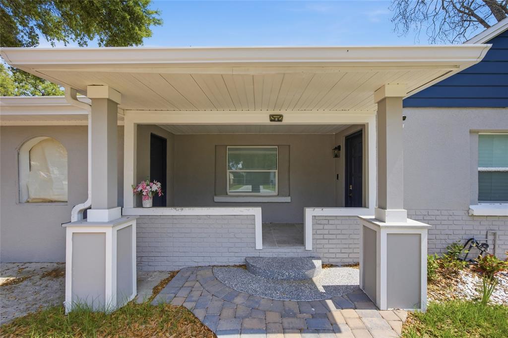 A covered front porch features a brick base, two support columns, and a stone walkway — 5809 N 17TH STREET, TAMPA, FL