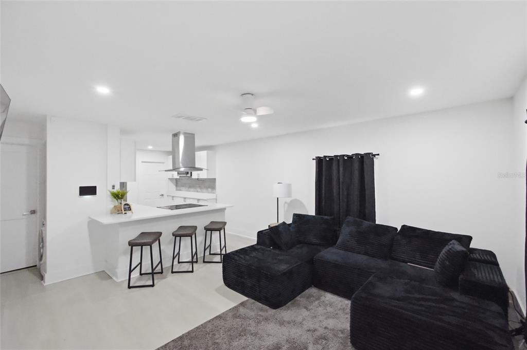 A modern open-concept living room features a black sectional sofa and a kitchen breakfast bar — 5809 N 17TH STREET, TAMPA, FL