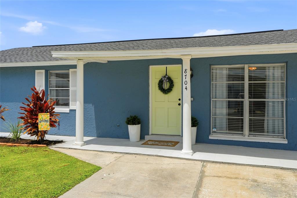 A living room with light gray walls, wood-look flooring, a vaulted ceiling, and a white door — 8704 MARLIN COURT, TAMPA, FL