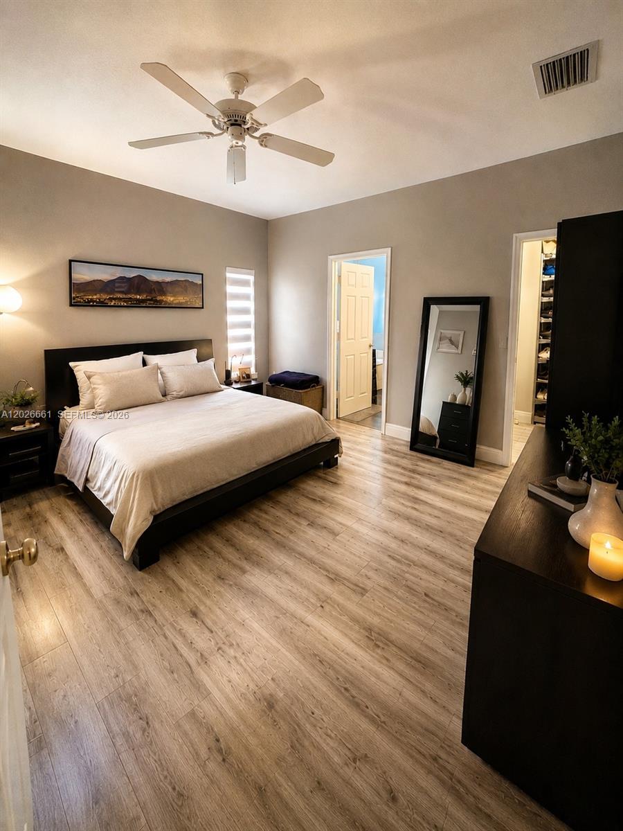 A bedroom features a king bed, wood-look flooring, a ceiling fan, and an attached closet — 13704 SW 31st St, Miramar FL 33027, MIRAMAR, FL