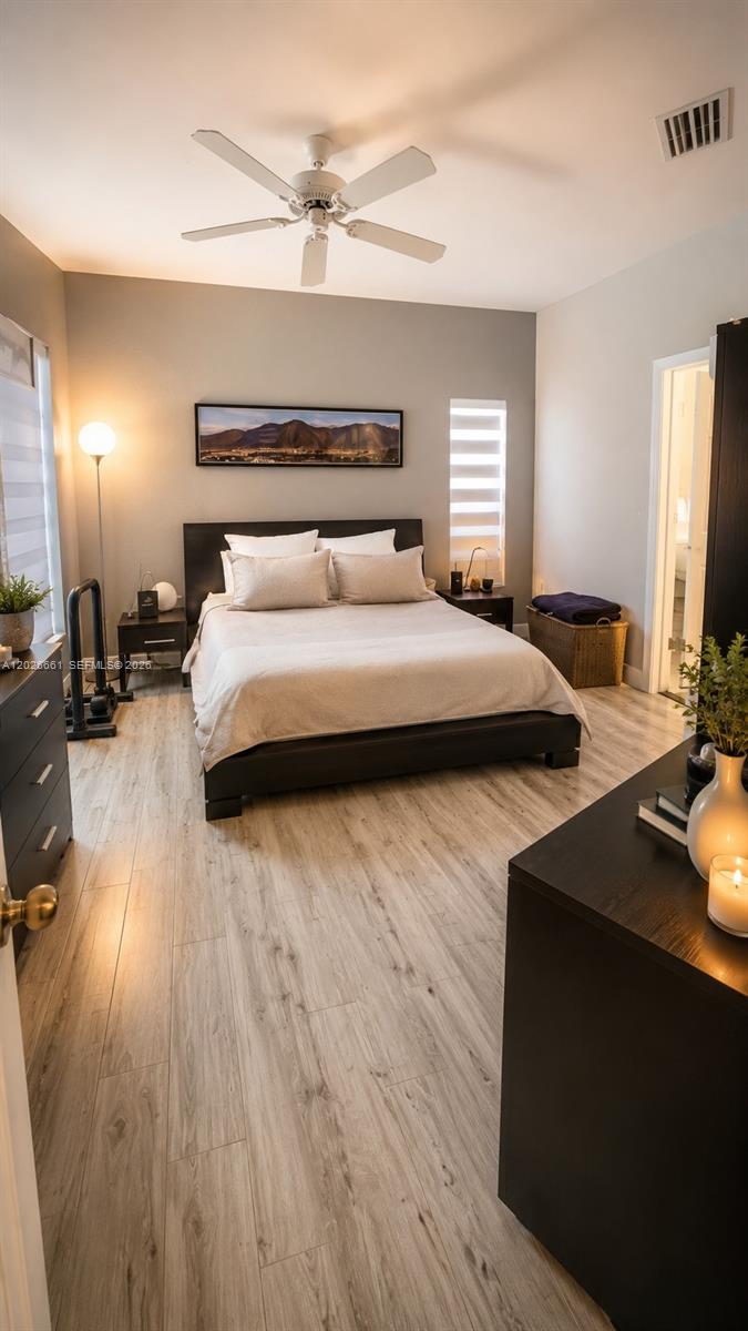 A bedroom features a bed with light bedding, a ceiling fan, and wood-look flooring — 13704 SW 31st St, Miramar FL 33027, MIRAMAR, FL