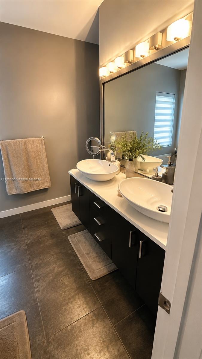 A bathroom features a double vanity with vessel sinks, dark cabinets, and a large mirror — 13704 SW 31st St, Miramar FL 33027, MIRAMAR, FL