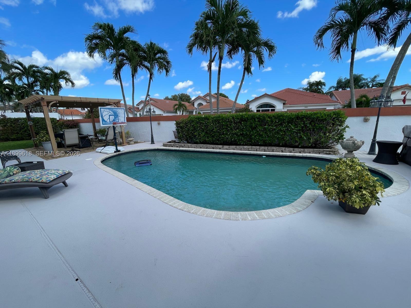 A backyard features a swimming pool, a pergola, palm trees, and a basketball hoop — 6953 Columbia Court, Margate FL 33063, MARGATE, FL