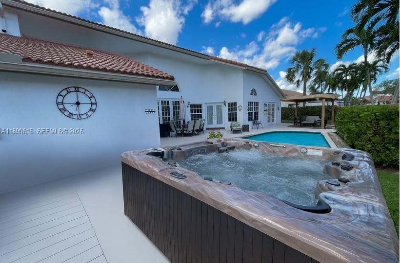 A hot tub sits on a deck next to a house with a swimming pool — 6953 Columbia Court, Margate FL 33063, MARGATE, FL