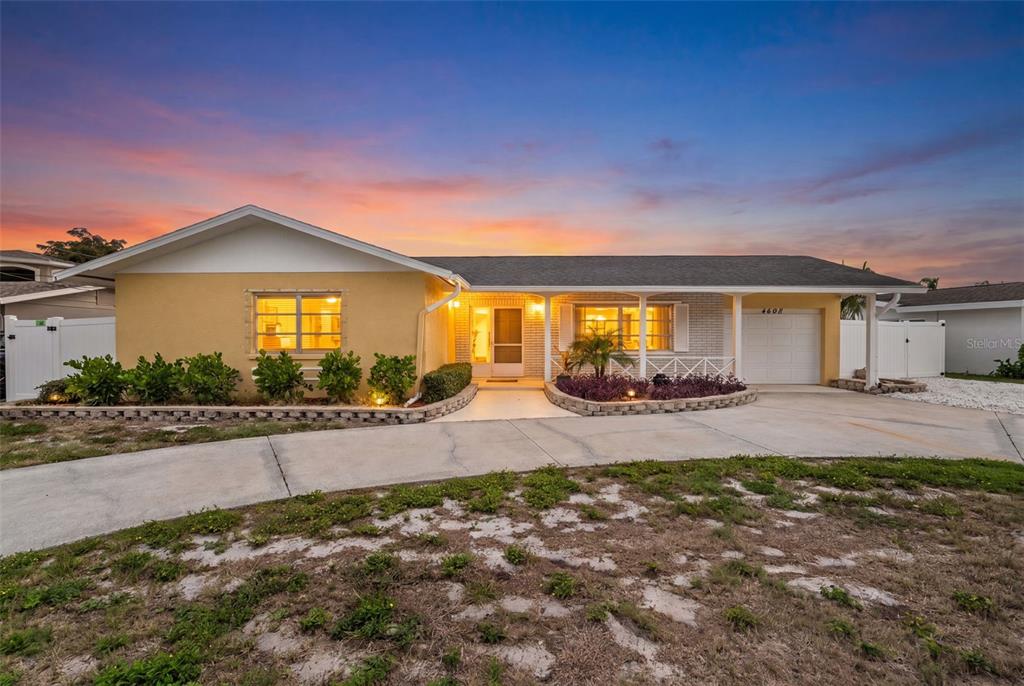 A single-story house with a yellow exterior, a concrete driveway, and a sunset sky — 4608 ARLINGTON ROAD, PALMETTO, FL