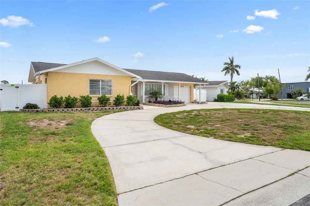 A yellow single-story house features a curved concrete driveway and a white privacy fence — 4608 ARLINGTON ROAD, PALMETTO, FL