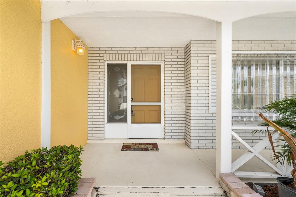 A covered front porch features a tan door, white brick accents, and yellow exterior walls — 4608 ARLINGTON ROAD, PALMETTO, FL