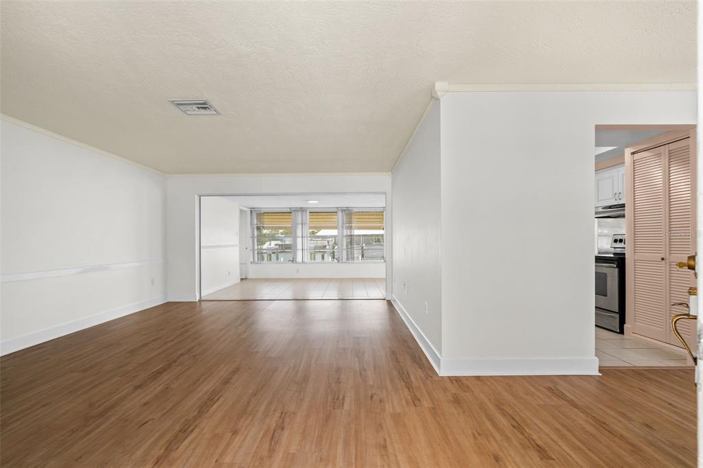 A living room with wood-look flooring leads to a sunroom with large windows — 4608 ARLINGTON ROAD, PALMETTO, FL