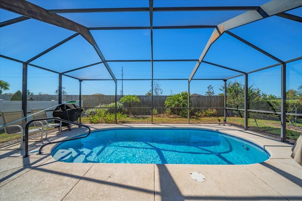 A swimming pool enclosed by a screened lanai with a concrete deck and backyard fence — 364 LAKE SUZANNE DRIVE, LAKE WALES, FL