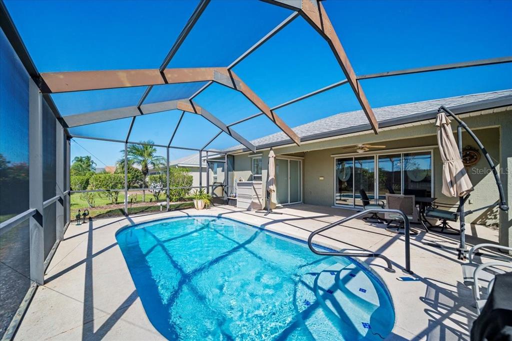 A swimming pool with a screen enclosure sits on a patio behind a house — 364 LAKE SUZANNE DRIVE, LAKE WALES, FL