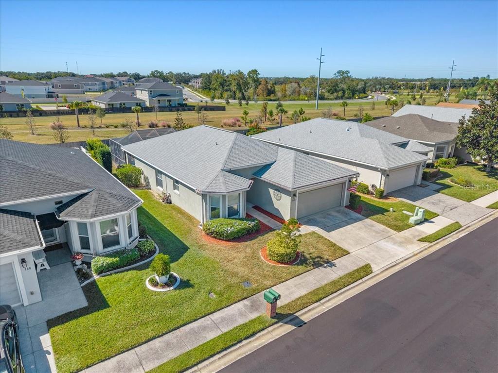 An aerial view shows three suburban houses with gray roofs and concrete driveways — 364 LAKE SUZANNE DRIVE, LAKE WALES, FL
