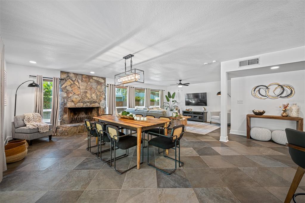 A dining area with a stone fireplace and tile flooring opens into a living room — 7259 131ST STREET, SEMINOLE, FL