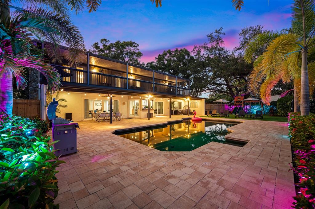 A two-story house with a balcony overlooks a backyard swimming pool and paved patio area — 7259 131ST STREET, SEMINOLE, FL