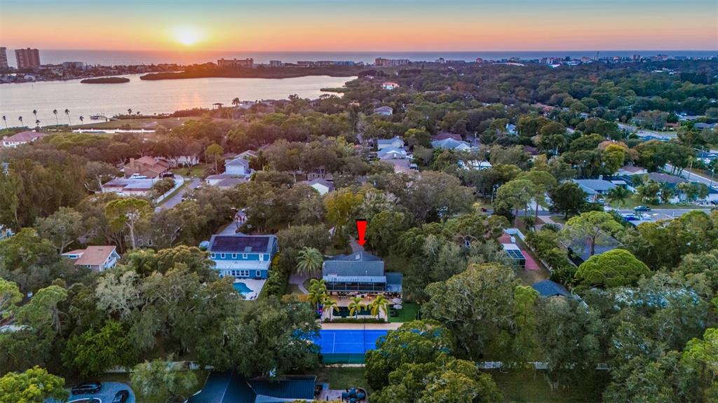 An aerial view shows a house with a blue tennis court and pool at sunset — 7259 131ST STREET, SEMINOLE, FL