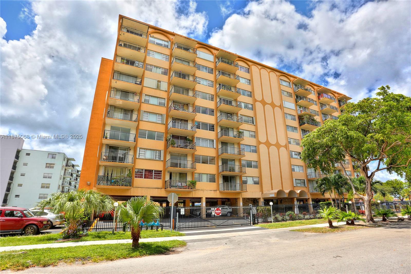 A multi-story orange apartment building features stacked balconies and a ground-level parking area — 1470 NE 125th Ter, North Miami FL 33161, NORTH MIAMI, FL